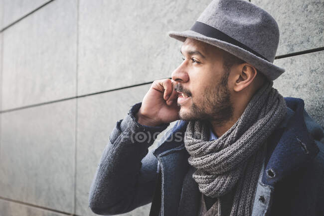 Close up of businessman leaning against wall talking on smartphone — Stock Photo