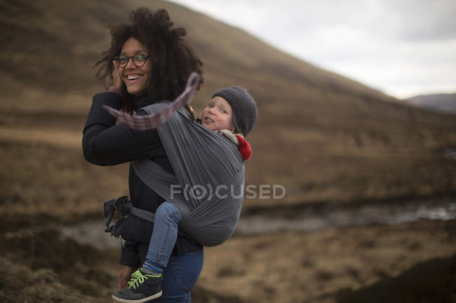 Mother carrying son in sling — Stock Photo