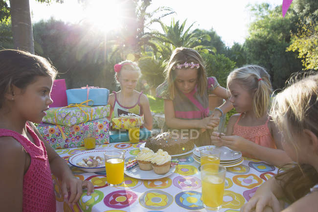 Meninas cortando bolo de aniversário com amigos — Fotografia de Stock