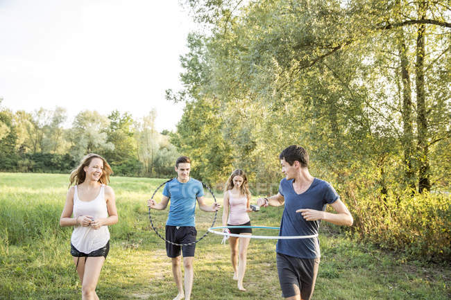 Group of friends in field, using hula hoops — Stock Photo