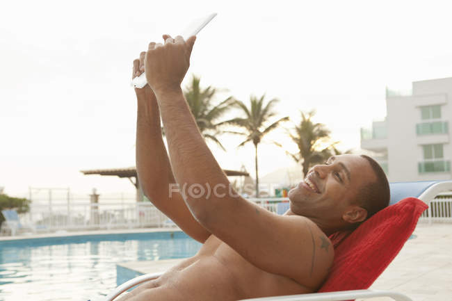 Взрослый мужчина, делающий цифровое селфи в бассейне отеля, Рио-де-Жанейро, Бразилия — стоковое фото
