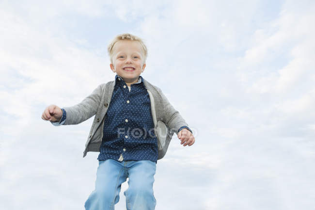 Glücklicher Junge mitten in der Luft gegen den Himmel — Stockfoto