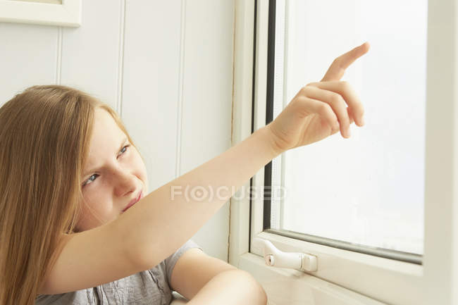 Fille pointant par la fenêtre de l'appartement de vacances — Photo de stock