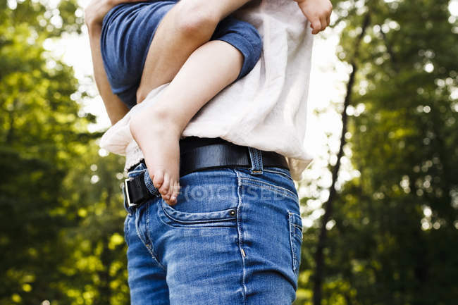 Plan recadré d'une femme adulte moyenne portant sa fille dans le parc — Photo de stock