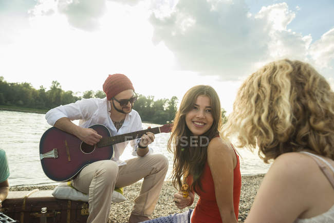 Giovane con amici che suonano la chitarra — Foto stock