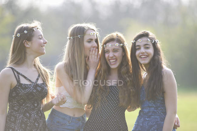 Vier Teenager-Mädchen mit Daisy-Chain-Kopfbedeckungen kichern im Park — Stockfoto