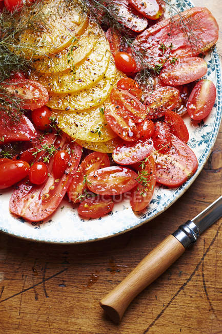 Various tomatoes sliced and seasoned on plate — Stock Photo