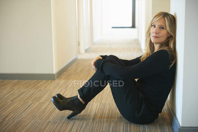Donna matura seduta contro il muro in corridoio — Foto stock
