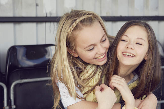 Портрет двух улыбающихся девушек, обнимающихся на трибуне стадиона — стоковое фото