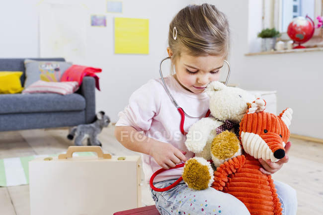 Chica jugando doctor a los juguetes blandos - foto de stock
