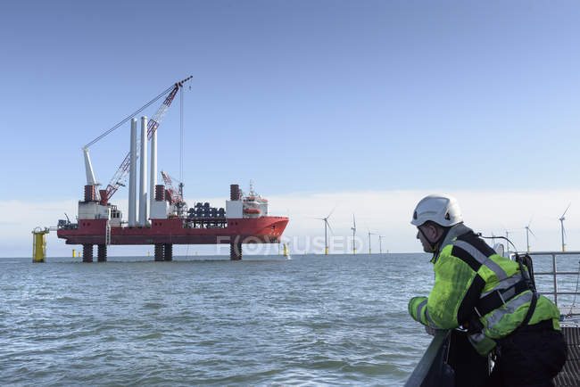 Worker looking at construction ship and offshore windfarm — Stock Photo