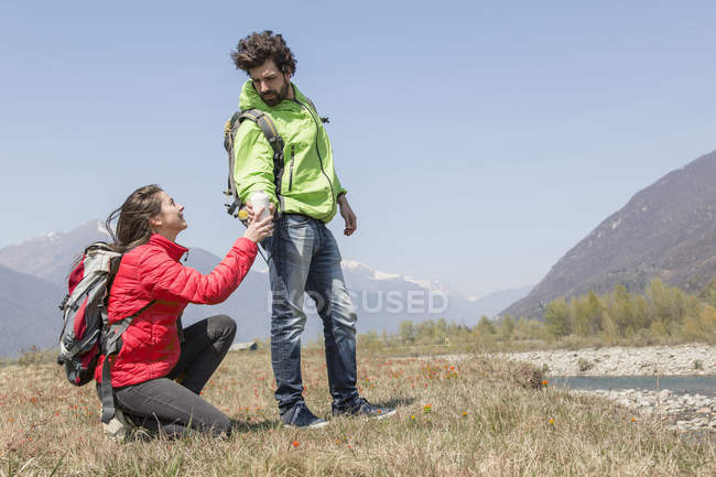 Young female hiker handing water bottle to boyfriend, Vogogna, Verbania, Piemonte, Italy — Stock Photo