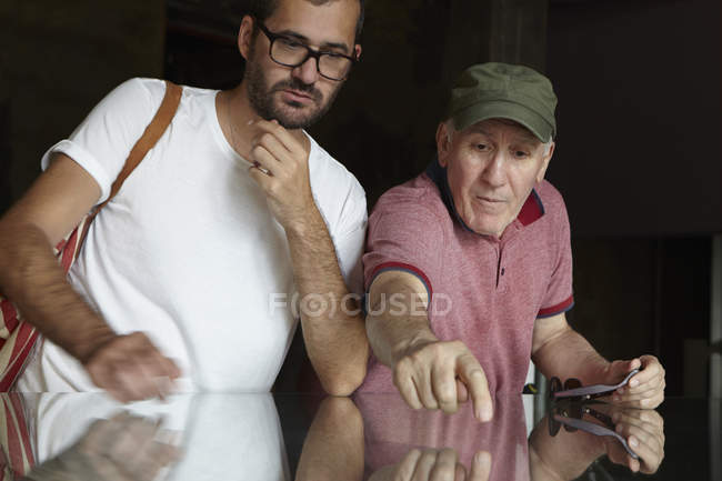 Mid adult man looking at senior man pointing — Stock Photo