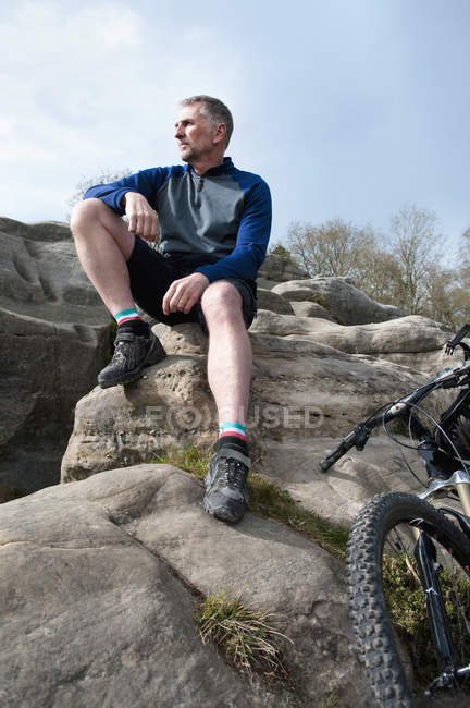 Ältere männliche Bergsteiger sitzen und schauen aus Felsformationen — Stockfoto
