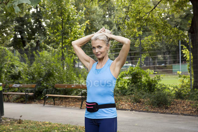 Зріла жінка зв'язує волосся під час тренувань у парку — стокове фото