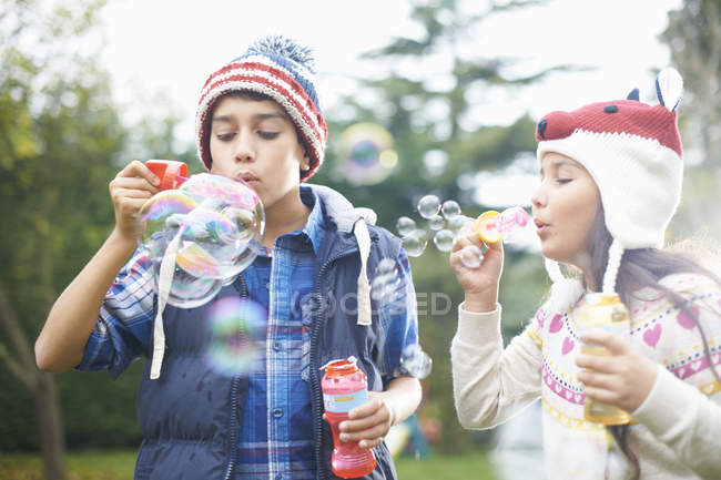 Siblings blowing bubbles in autumnal garden — Stock Photo