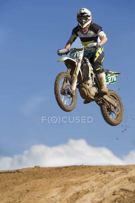 Junge männliche Motocross-Rennfahrer springen schlammigen Hügel — Stockfoto