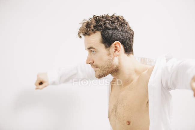 Young businessman putting on shirt in apartment — Stock Photo