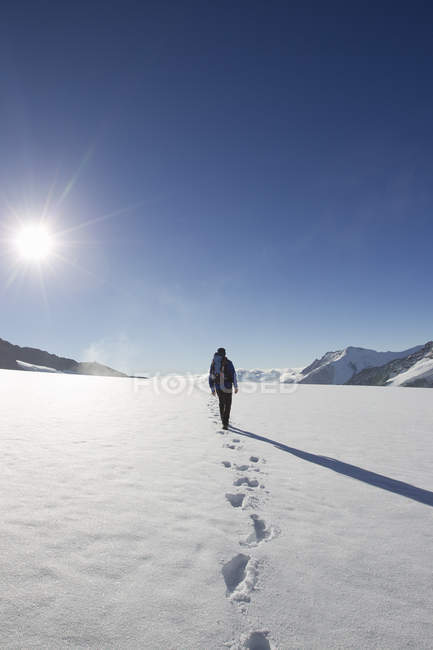 Rear view of male hiker and snow footprints, Jungfrauchjoch, Grindelwald, Switzerland — Stock Photo