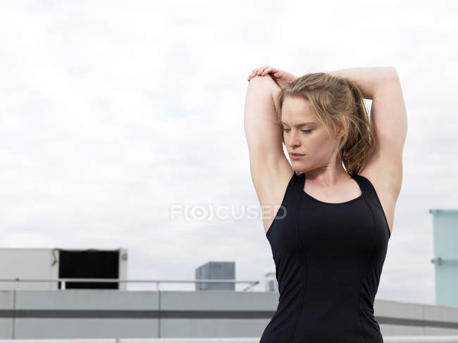 Young woman doing warm up training in parking lot — Stock Photo