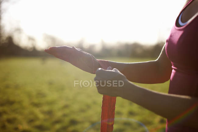 Cropped view of mature female boxer bandaging hands in field — Stock Photo