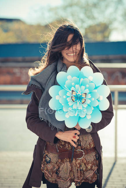 Portrait of mid adult woman with flower windmill — Stock Photo