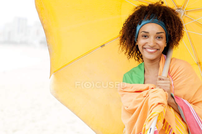 Молода жінка позує з парасолькою на пляжі — стокове фото