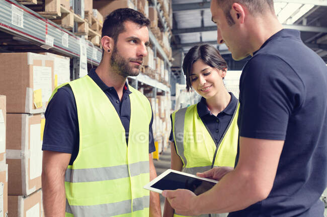 Warehouse workers using digital tablet in distribution warehouse — Stock Photo