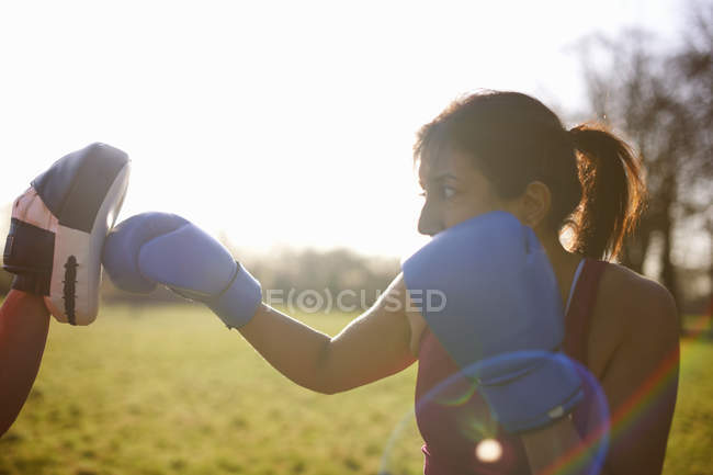 Mature woman boxer training in field — Stock Photo