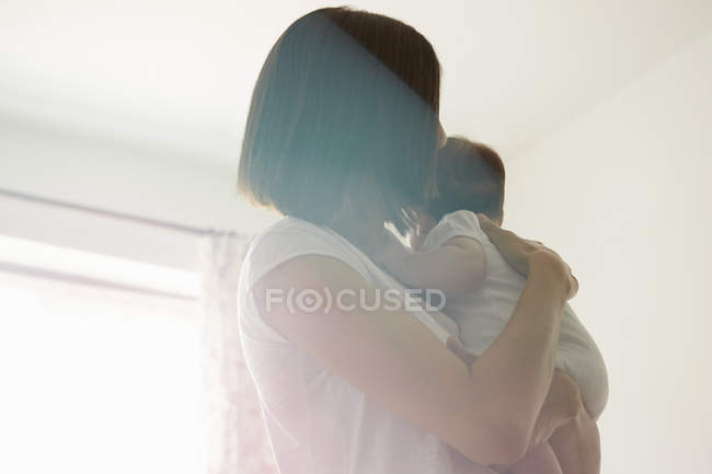 Madre portadora de bebé en el dormitorio, enfoque selectivo - foto de stock