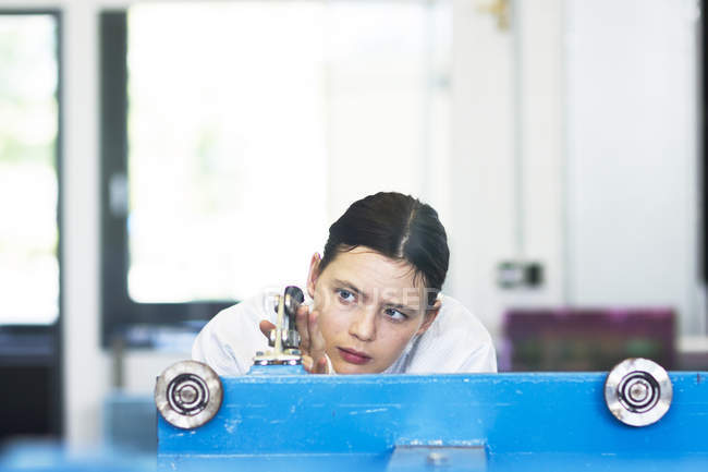 Head and shoulders of young woman operating machine — Stock Photo