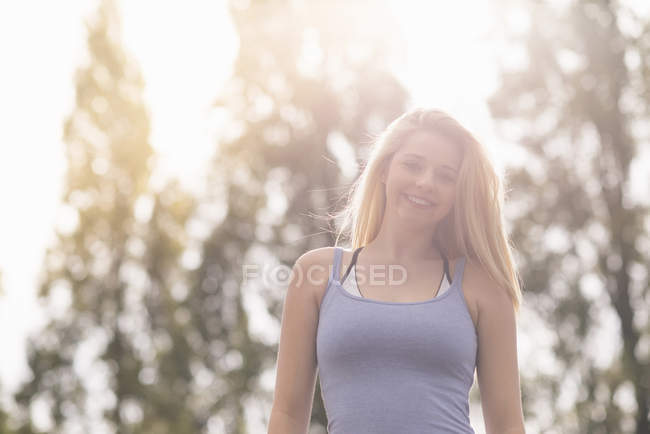 Mujer joven de pie contra la luz del sol - foto de stock