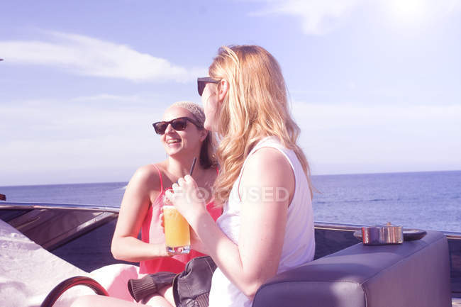 Дві дорослі друзі-жінки сміються на яхті — стокове фото