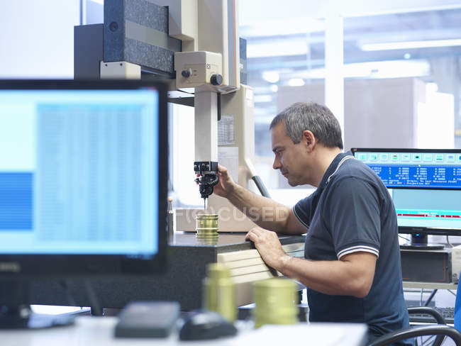 Trabajador masculino inspeccionando piezas en fábrica de ingeniería - foto de stock