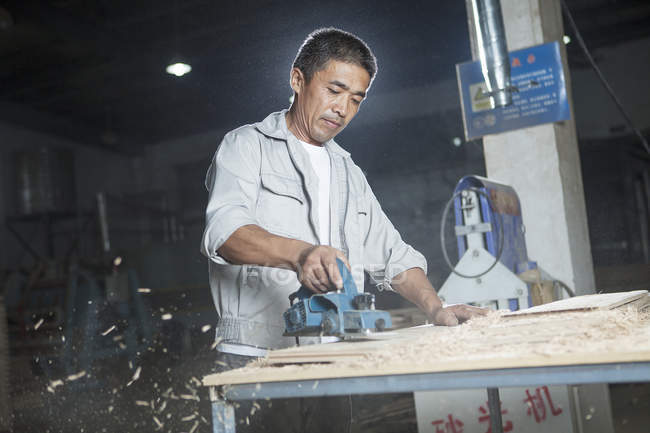 Carpenter cutting wooden plank in factory, Jiangsu, China — Stock Photo