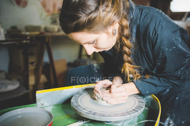 Young woman with plaited hair using pottery wheel — Stock Photo