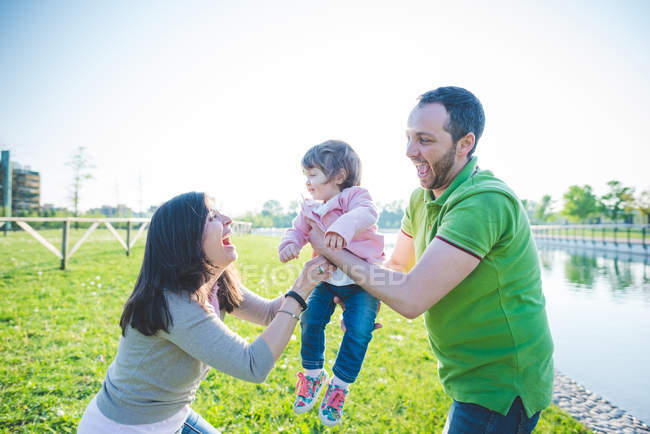 Casal entregando a filha da criança um ao outro no parque — Fotografia de Stock
