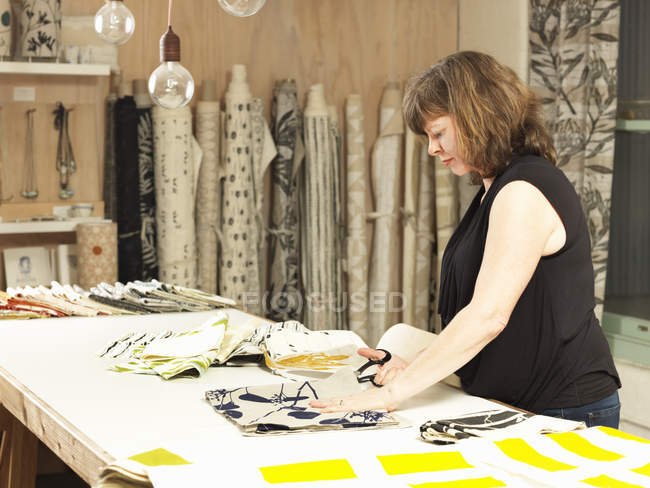 Tela de corte mujer en mesa de trabajo en taller textil impreso a mano - foto de stock