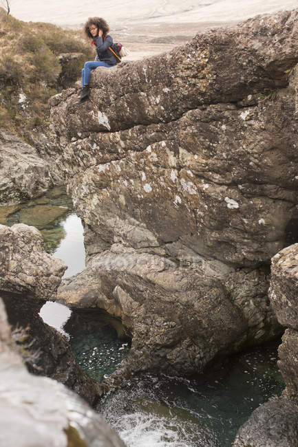 Mujer sentada sobre rocas, Piscinas de hadas, Isla de Skye, Hébridas, Escocia - foto de stock