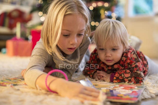 Hermanas mirando el calendario de adviento en casa en Navidad - foto de stock