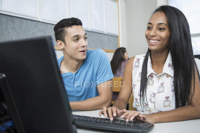 Dos adolescentes escribiendo en la clase de informática de la escuela secundaria - foto de stock