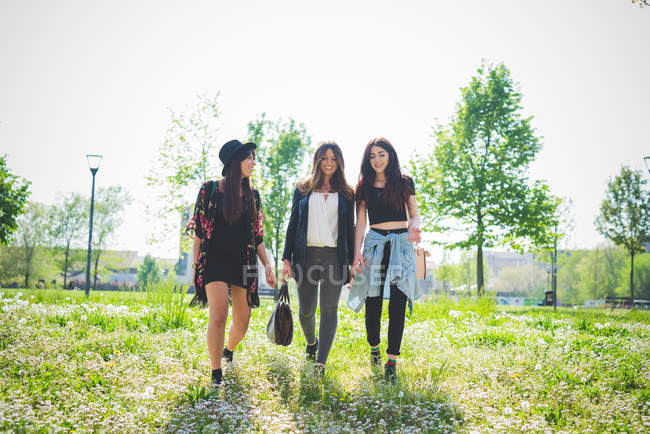Three young female friends strolling in park — Stock Photo