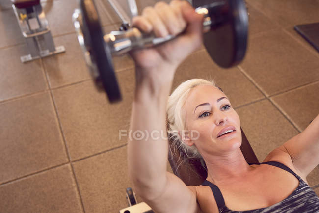 Женщина тренируется с гантелями в спортзале — стоковое фото