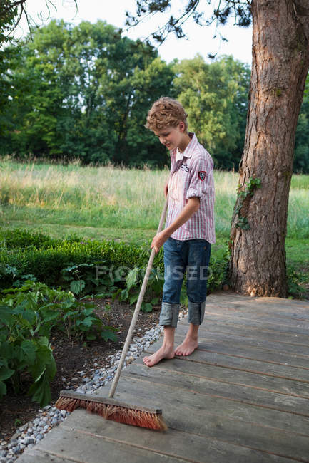 Boy sweeping the porch — Stock Photo