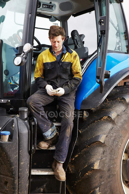 Agriculteur utilisant un téléphone portable sur tracteur — Photo de stock