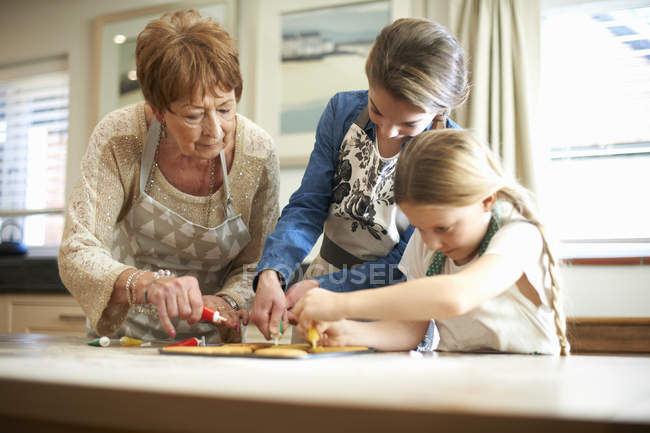 Seniorin und Enkelinnen schmücken Christbaumkuchen — Stockfoto