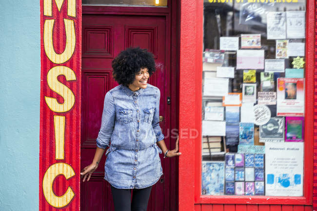 Ritratto di donna matura che sbircia dalla porta del negozio di musica — Foto stock