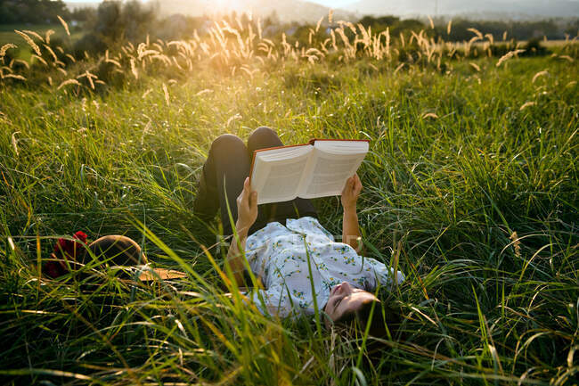Femme couchée dans l'herbe lecture — Photo de stock