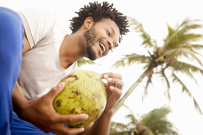 Mid adult man sitting on wall with coconut, Rio De Janeiro, Brazil — Stock Photo
