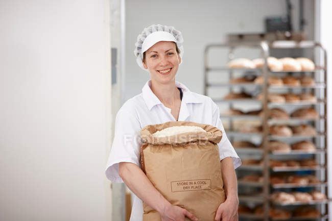 Chef llevando saco de harina en la cocina - foto de stock